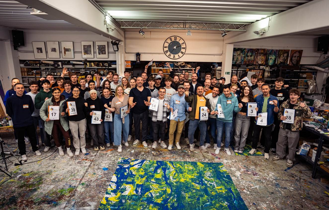 Vorbereitungsevent zu "The Colourful Art of Football". Der Künstler Christian Nienhaus (erste Reihe, Bild-Mitte, schwarzes T-Shirt) mit allen Freiwilligen, die am 5.5. an dem Fußball-Kunstwerk und dem Rekordversuch, das "größte Bild der Welt" zu erstellen, beteiligt sein werden. (Bildrechte: Christian Nienhaus / TAS Emotional Marketing)