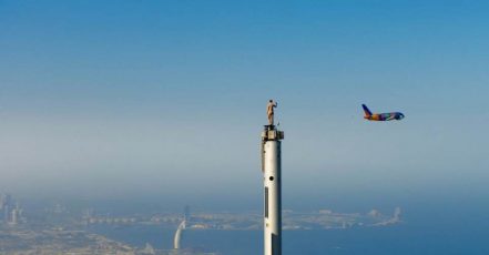 Bild: Doppel-Wow! Mutige Emirates Stuntfrau winkt auf der Spitze des Burj Khalifa, Dubai, dem tieffliegenden A380 im Expo-Design zu. (Bildquelle: Emirates)
