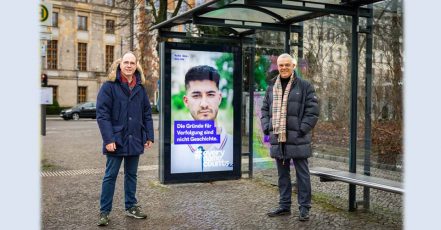 Bild: Kampagnenmotiv neben dem Reichstagsgebäude. Patrick Möller, Geschäftsführer Wall GmbH, und Steffen Baumheier, stellv. Direktor Arolsen Archives, an einem digitalen Werbeträger mit dem Kampagnenmotiv. (Foto: Wall GmbH)