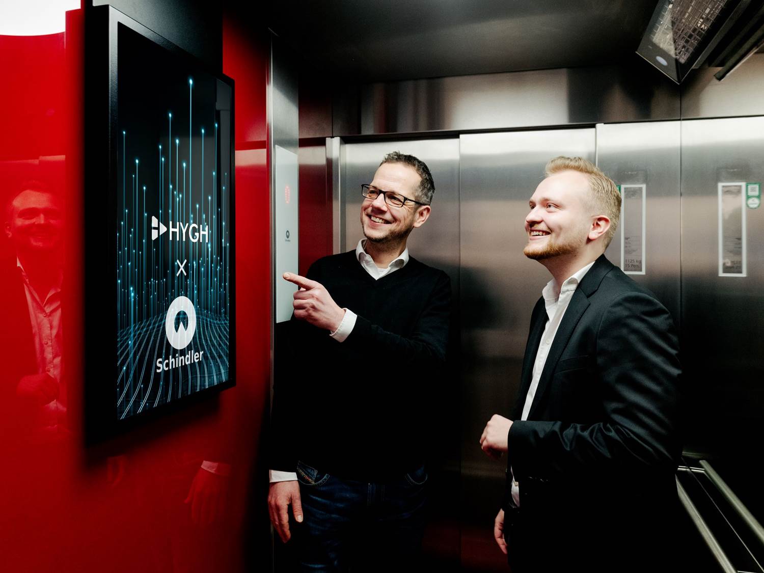 Neuer Touchpoint für Markenbotschaften: HYGH-Co-Founder Antonius Link (rechts im Bild) und Jan Steeger, Marketingleiter Schindler Deutschland, präsentieren digitale Werbeflächen in Wohngebäude-Aufzügen